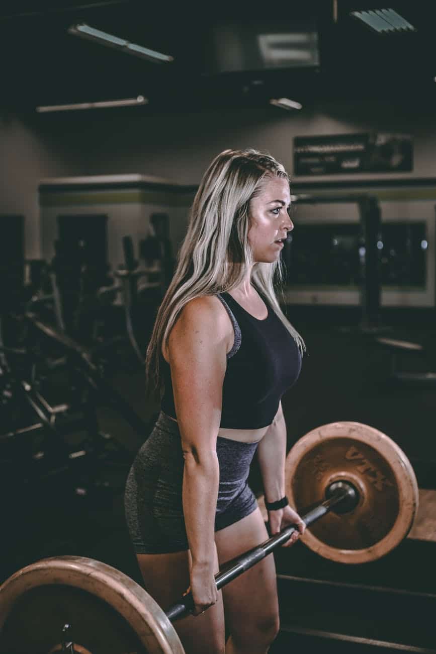 strong sportswoman lifting barbell while working out in gym