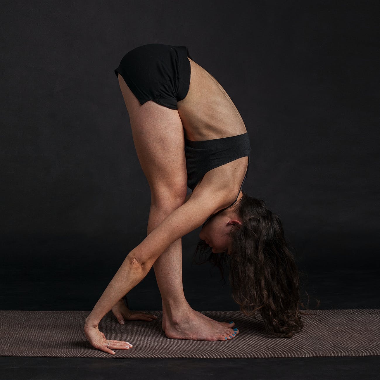 woman wearing black sports bra reaching floor while standing